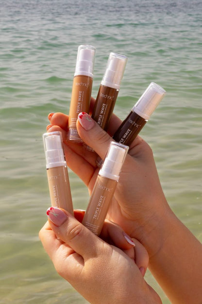 Female hands holding several shades of technic triple wave sundrenched concealers with beach water, background, natural summer glow