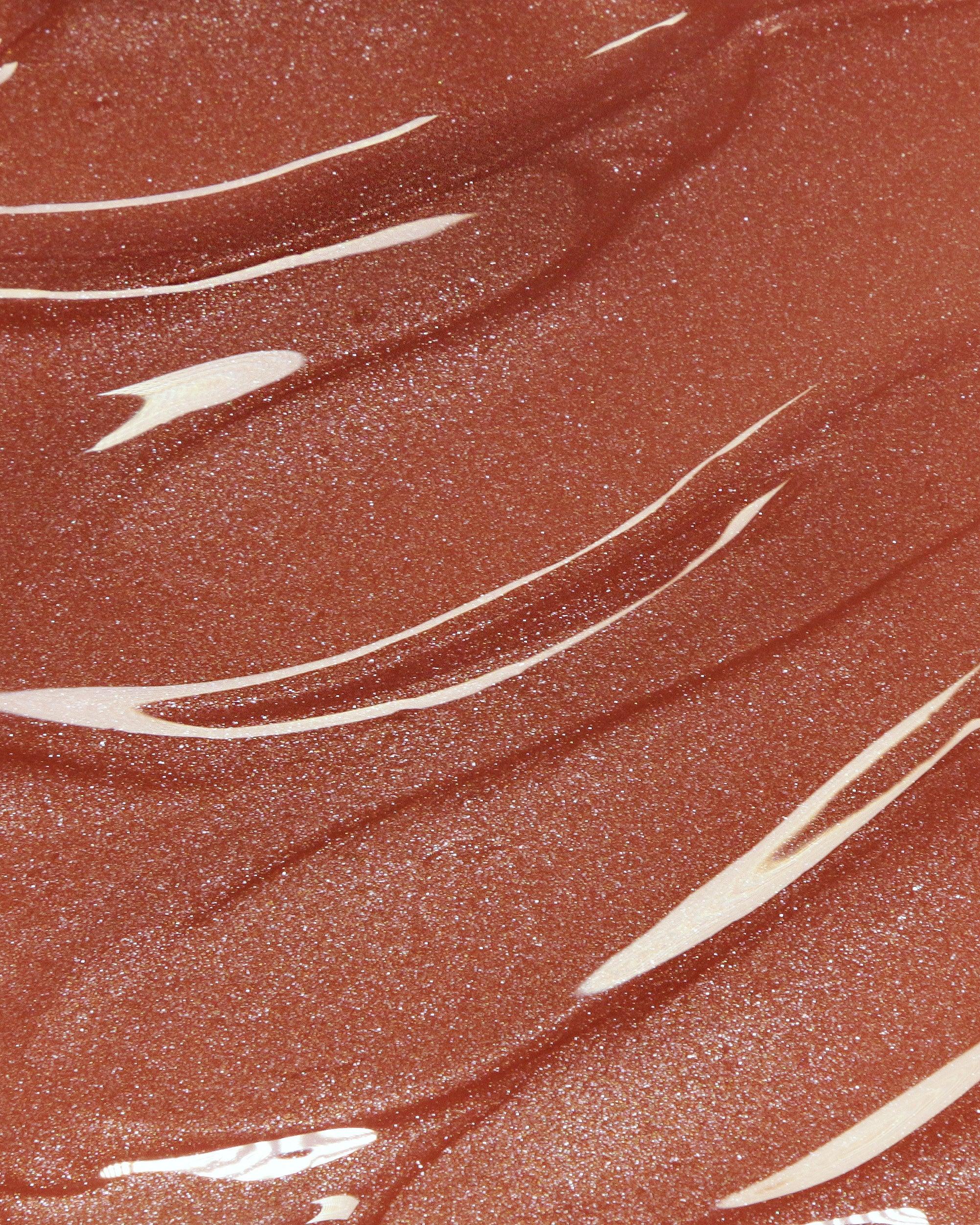 A close-up texture shot of a shimmery, warm terracotta-brown makeup cosmetic cream with glossy white swirled streaks.
